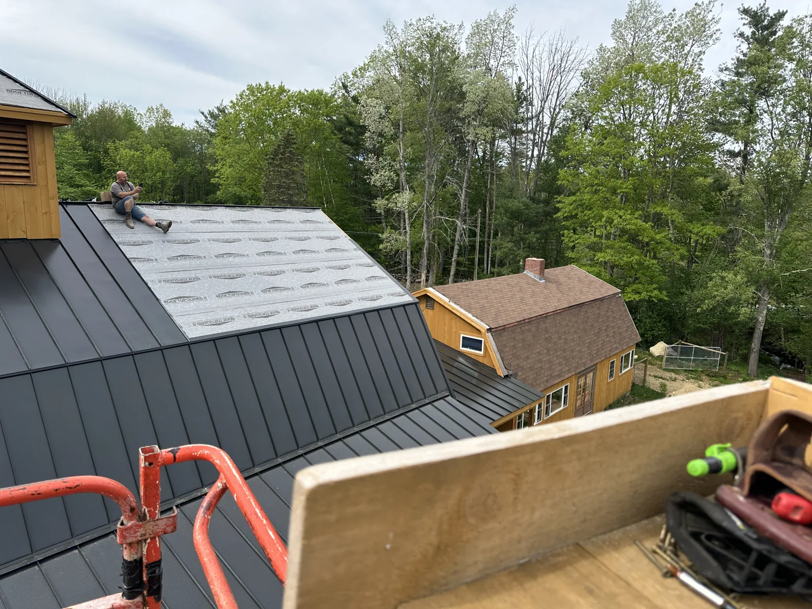 Standing-seam steel roofing going on with a lift
