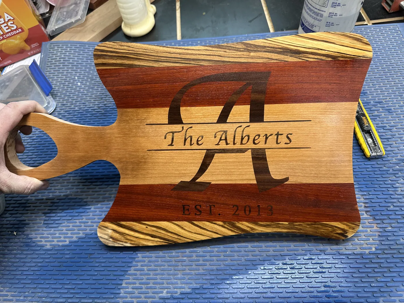 Paddle-handled serving board engraved with a monogram, family name, and established date.