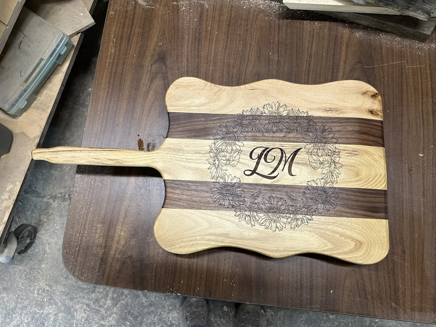 Walnut and hickory serving board engraved with a floral wreath around a script monogram.