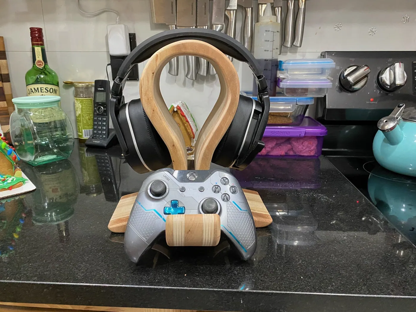 Maple desk stand that cradles a gaming headset above a fitted controller holder.