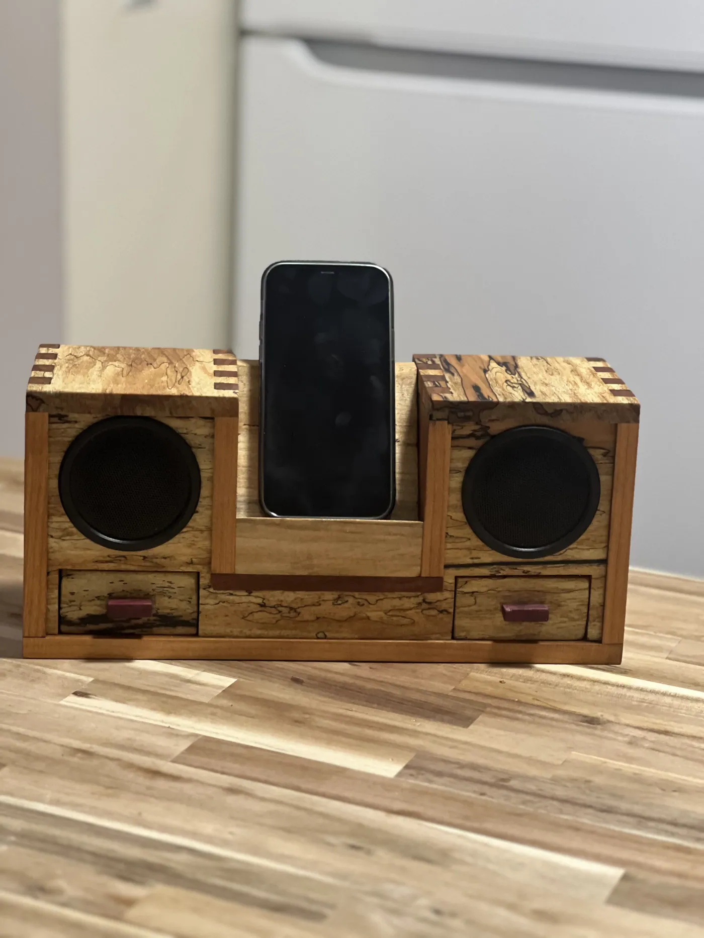 Desktop Bluetooth speaker and phone dock in spalted maple and cherry, with small drawers.