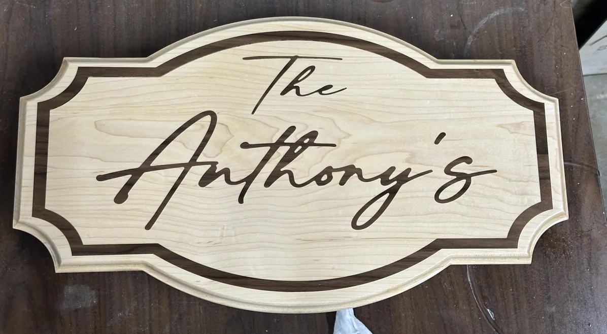 Scalloped maple family name sign with a walnut border and flowing script.